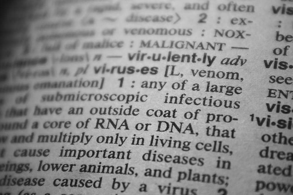 Black and white close-up of a dictionary page focusing on the definition of 'virus'.