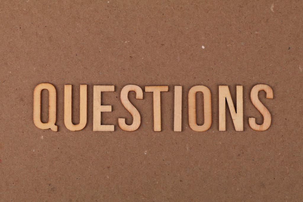 Wooden letters spelling the word "QUESTIONS" on a cardboard background, providing a neutral copyspace.