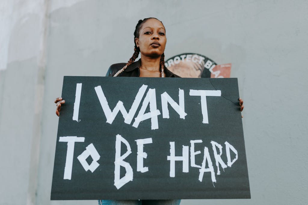 A young woman holds a protest sign outdoors, advocating for being heard.