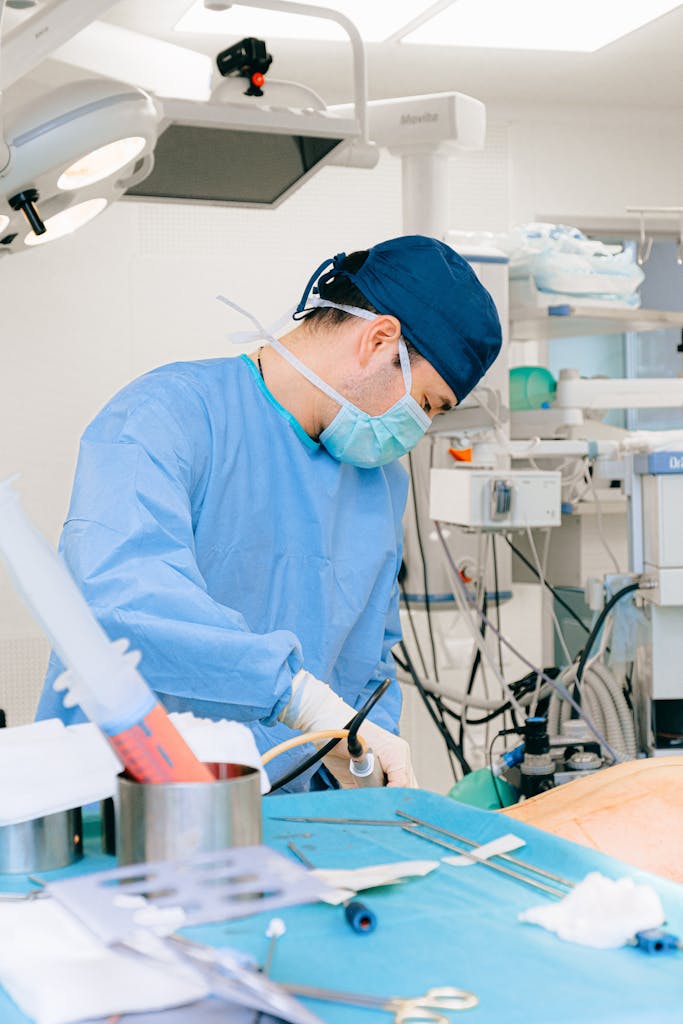 An adult male surgeon in scrubs performs surgery in an operating room.